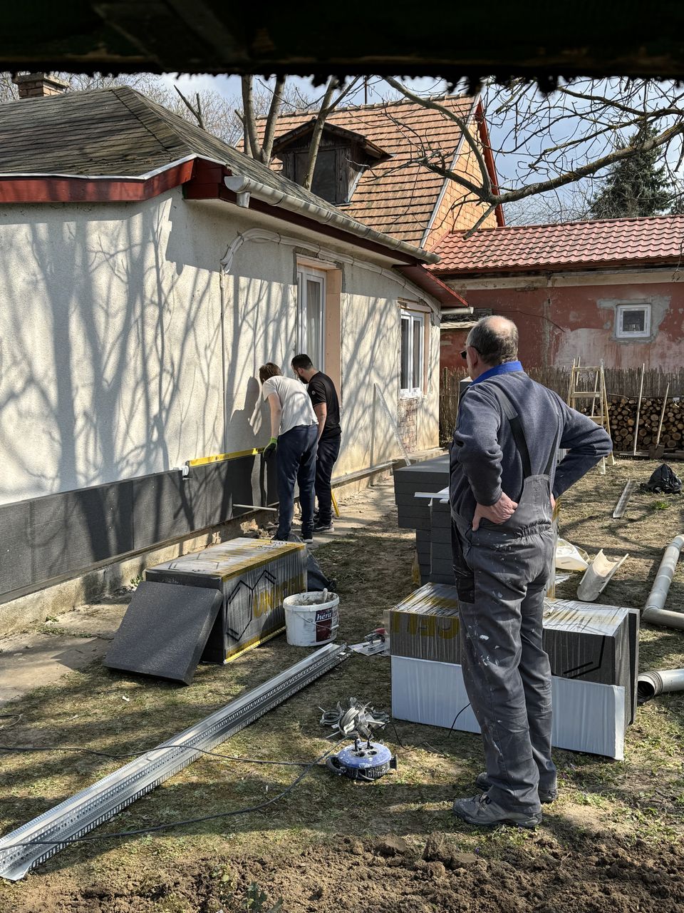 A csapat hőszigetelő lapokat ragaszt a ház homlokzatára